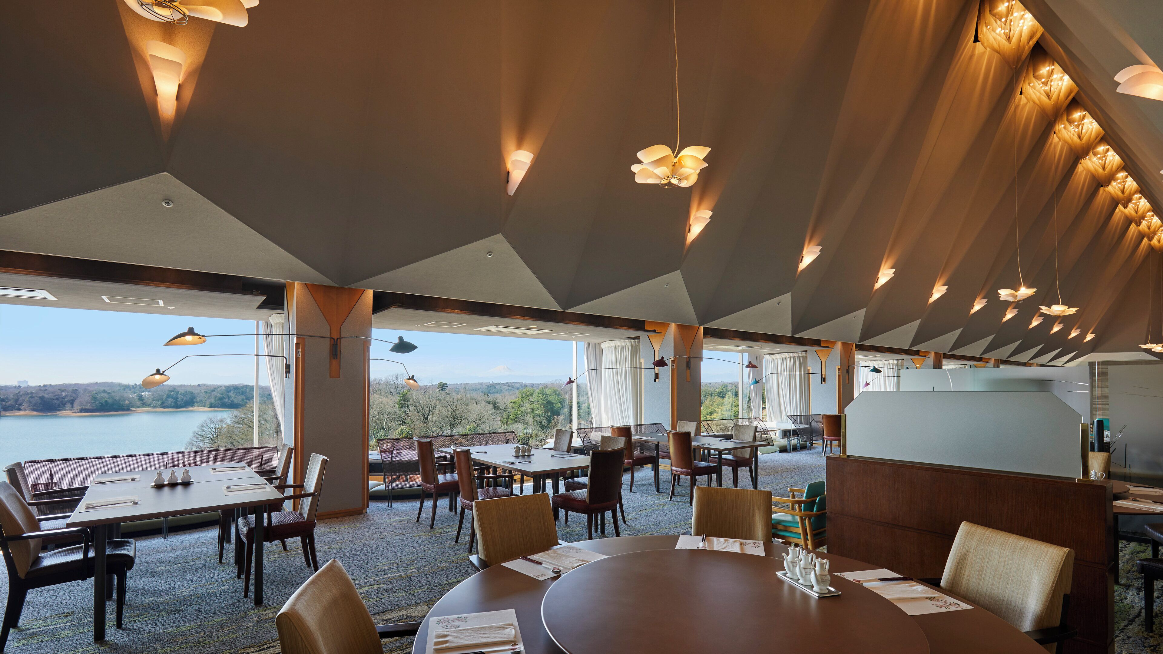 A restaurant with a view of a lake, featuring modern decor and multiple dining areas.