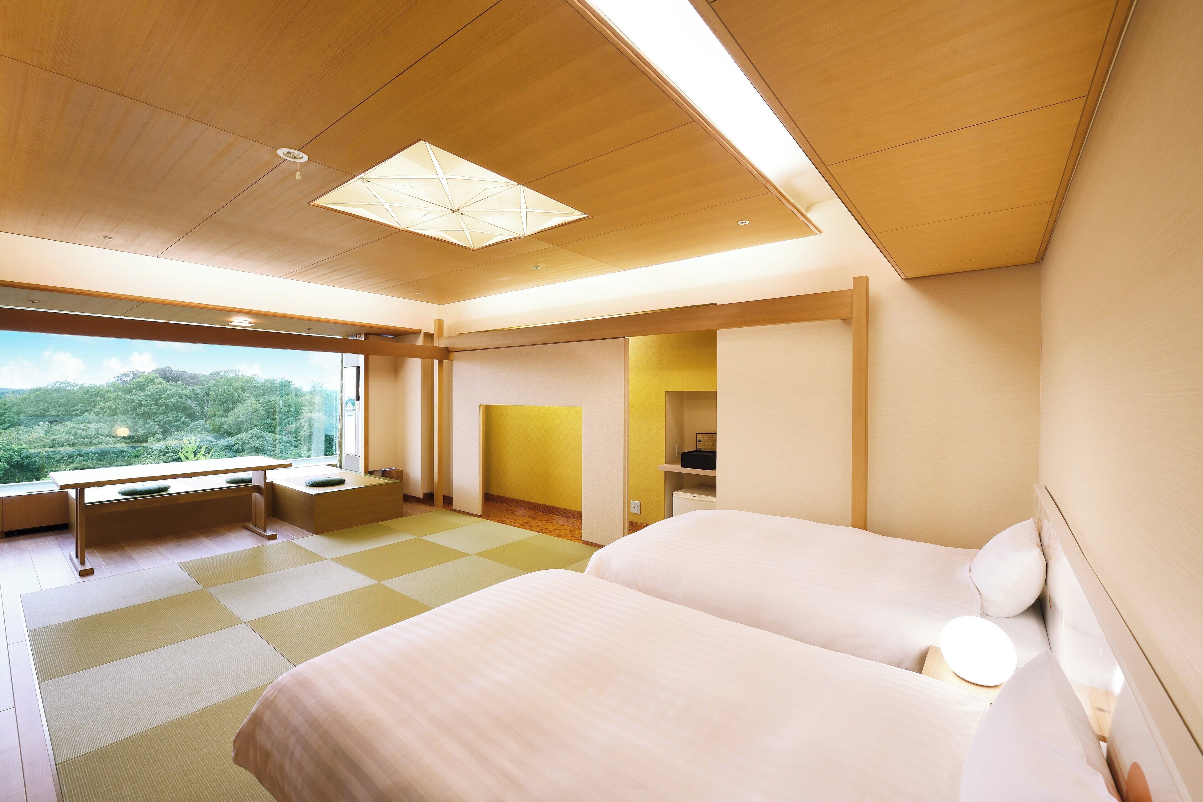 A modern hotel room with two beds, a desk, and a view of the outdoors.