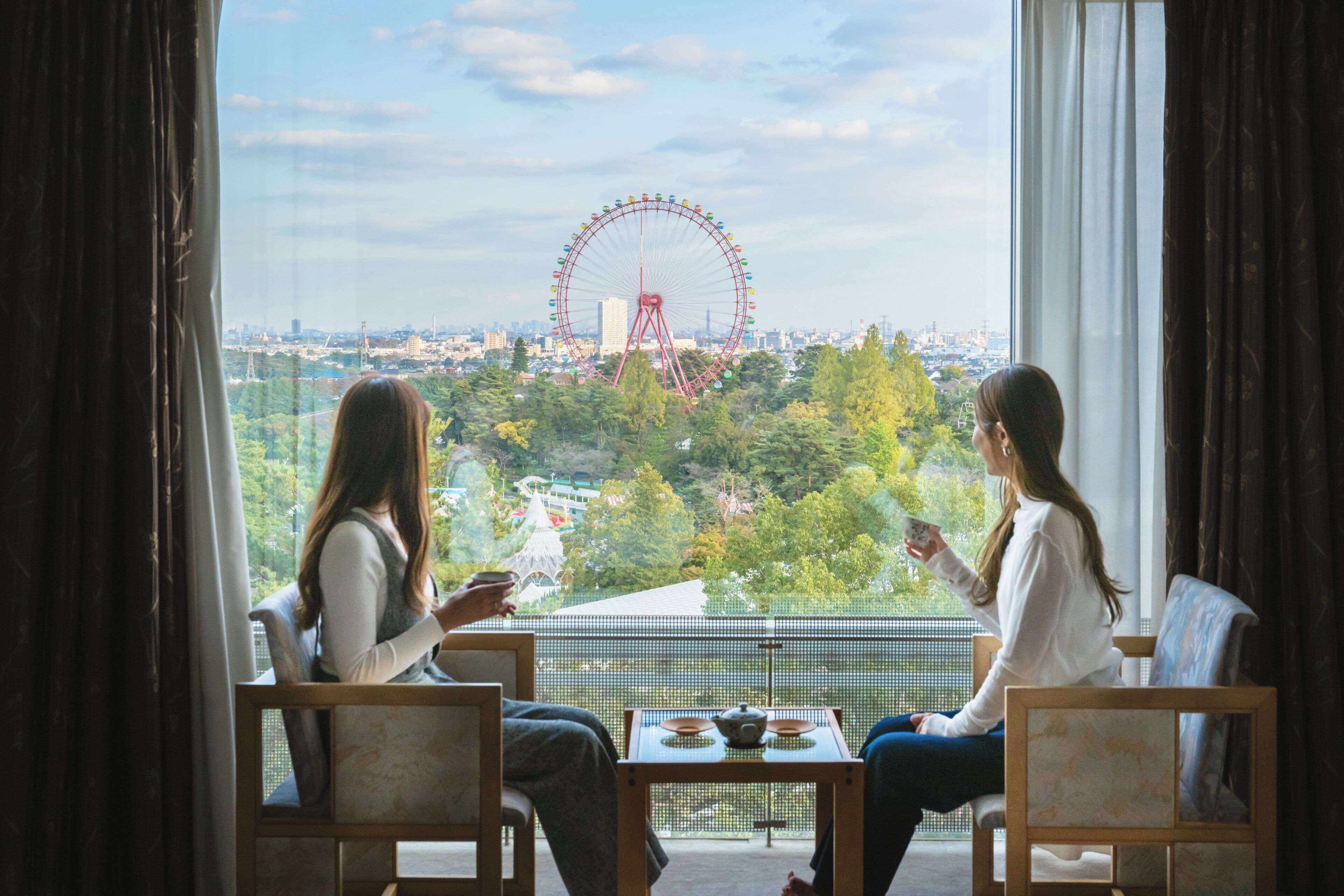 Två personer sitter vid ett bord med utsikt över en stadsbild och ett pariserhjul.
