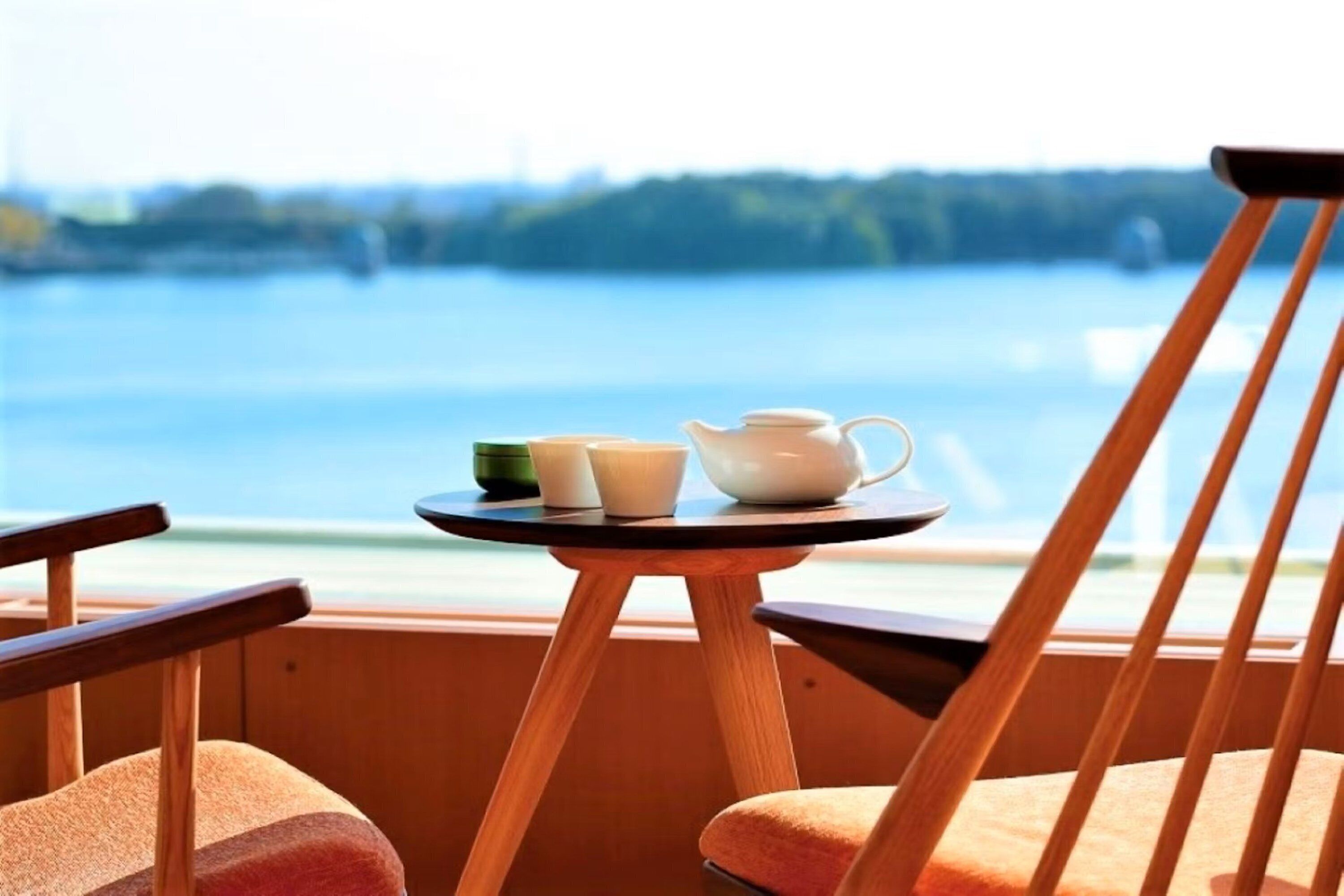 A wooden chair and table with a view of a lake.