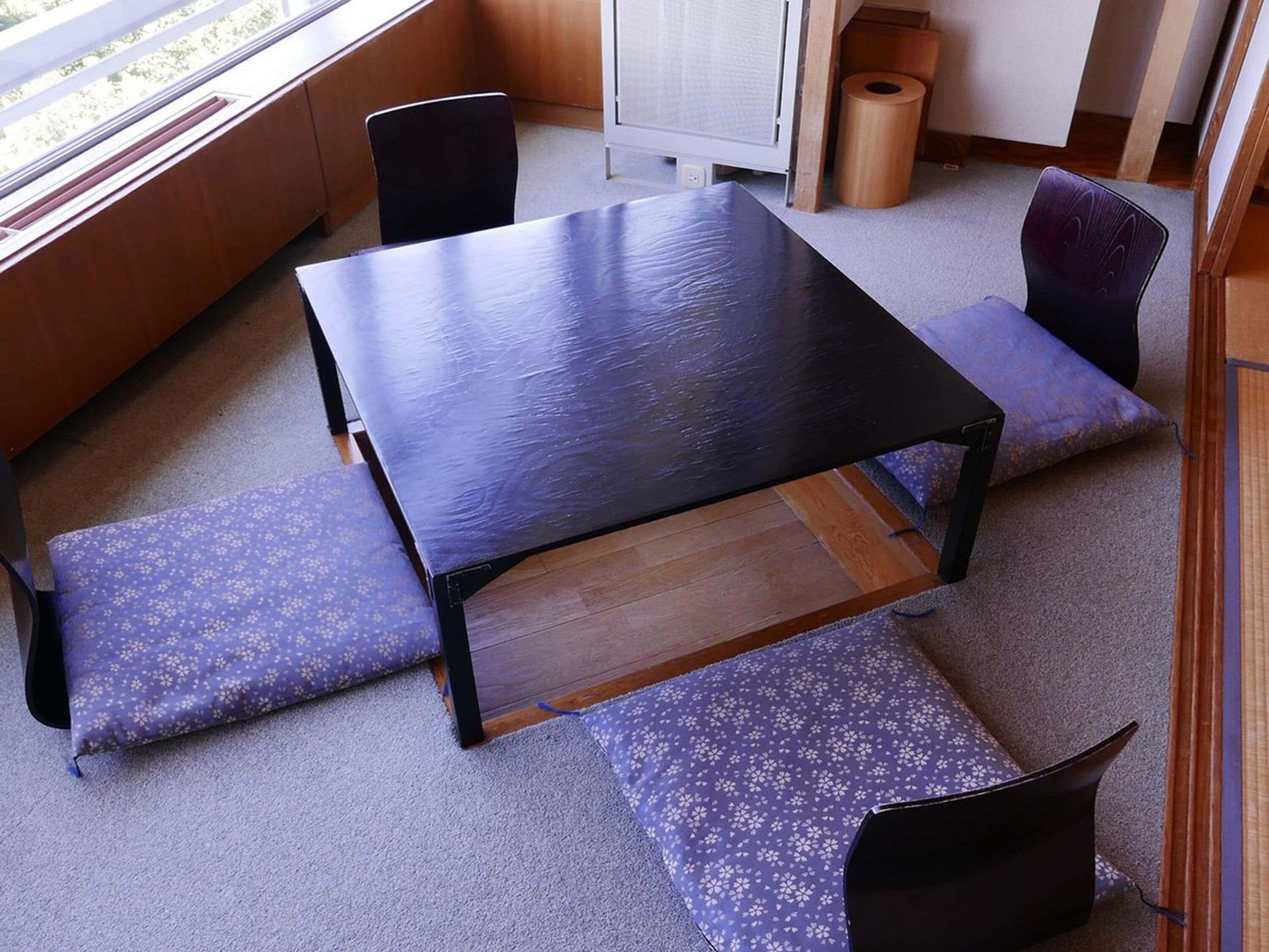 Une pièce avec une table en bois, quatre chaises et une fenêtre.