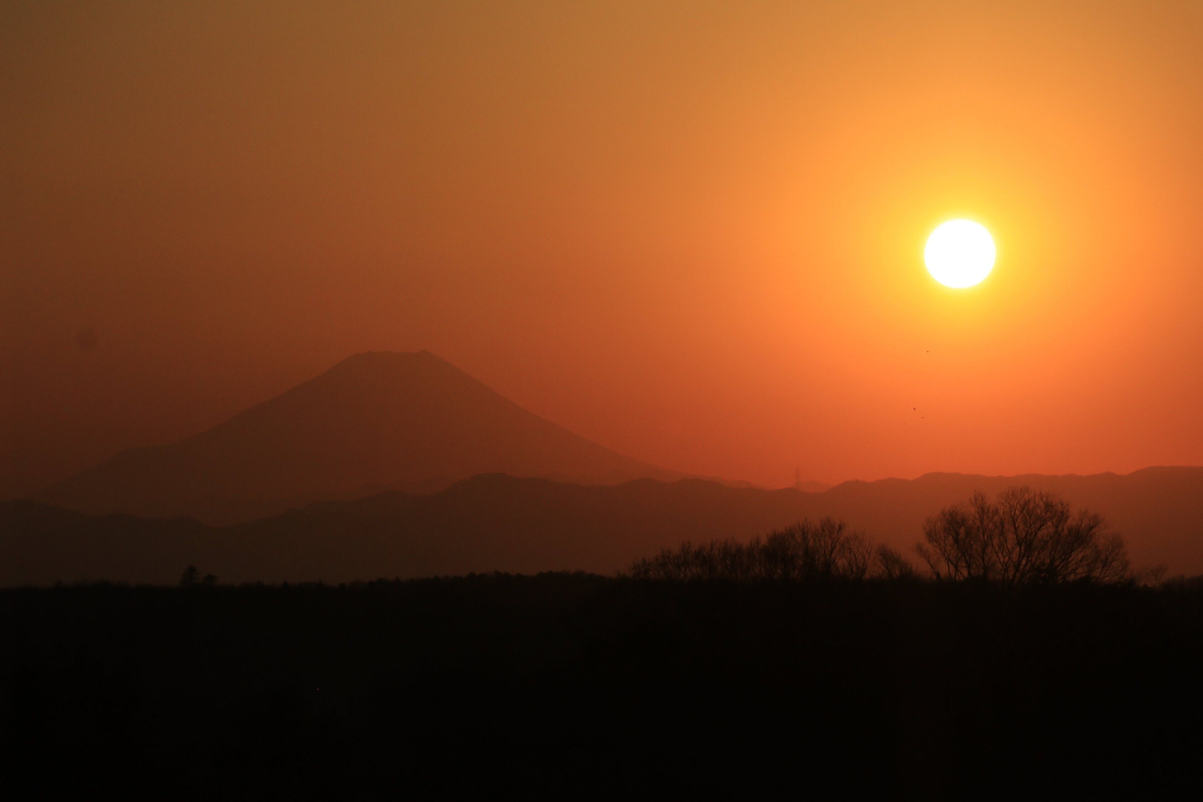 A sunset over a mountain range with a clear sky.