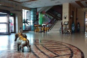 Un vestíbulo con piso de mármol, una escalera y estatuas decorativas.