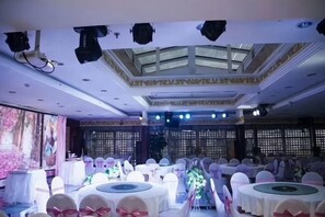 A banquet hall with round tables, chairs, and a stage. - Fushun Tiantian Hotel (Mudanjiang High-speed Railway Wanda Branch) (Mudanjiang)
