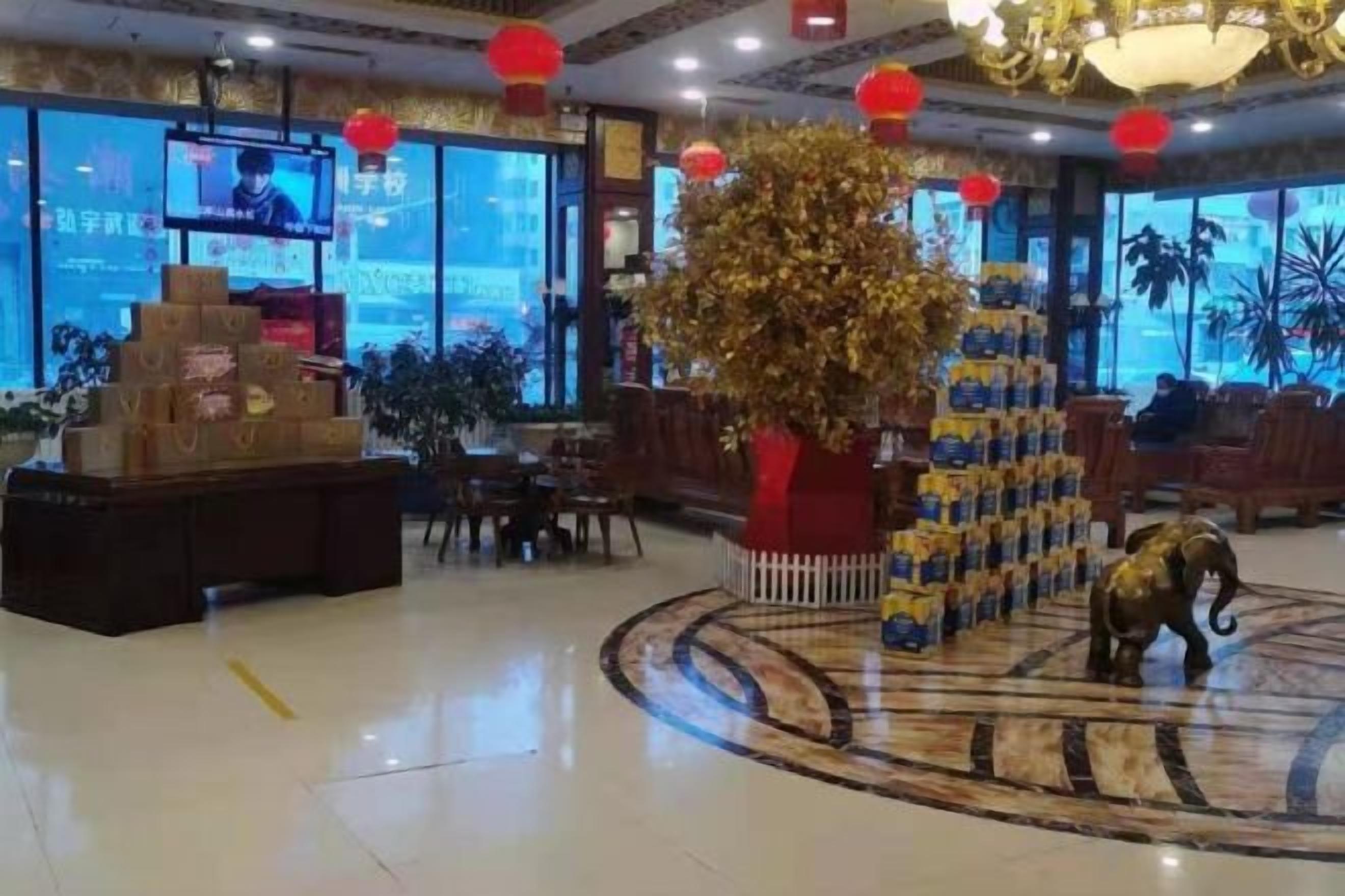 A hotel lobby with a reception desk, a large decorative tree, and a statue of an elephant.
