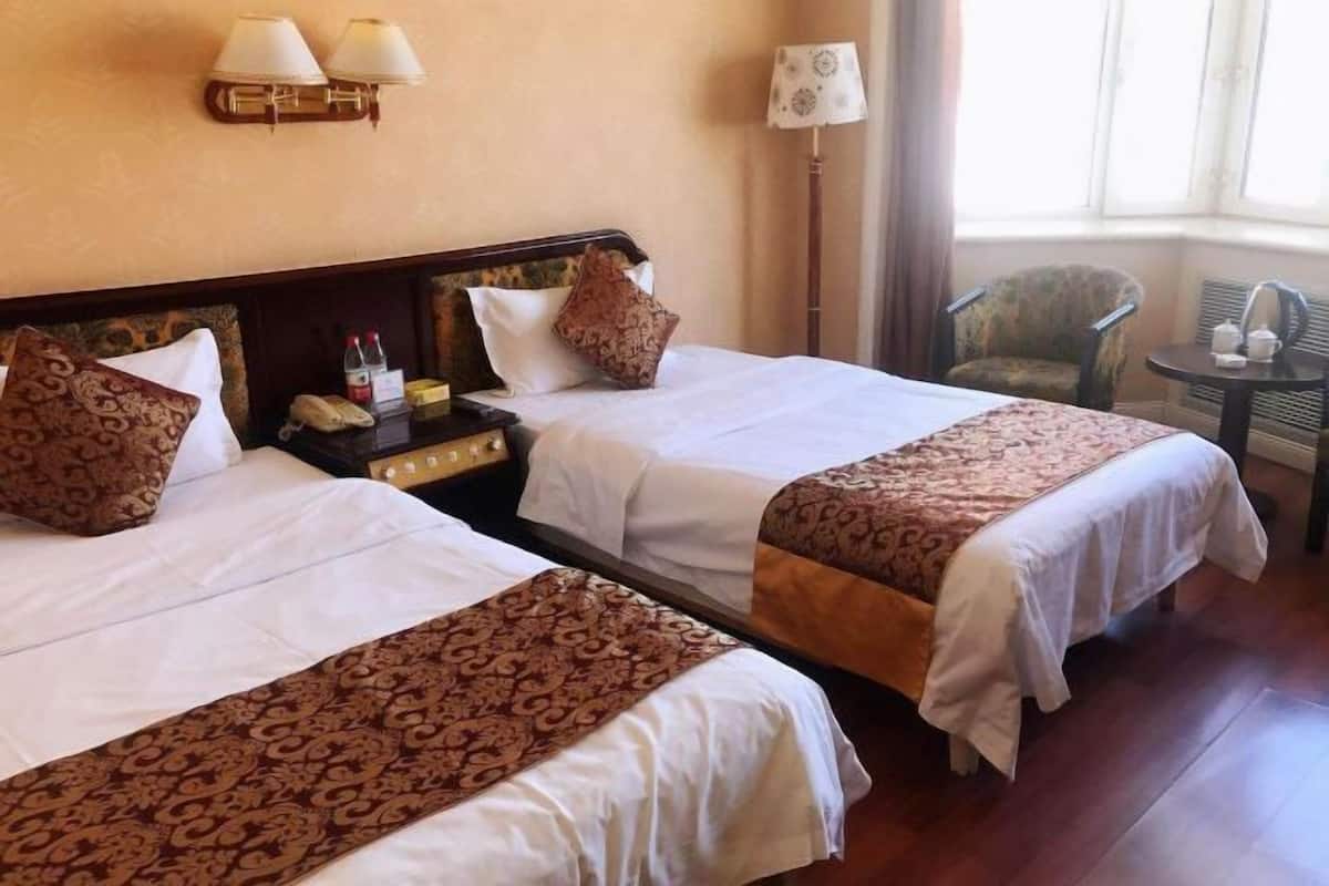 Une chambre d’hôtel avec deux lits, une table de chevet, une lampe, une chaise et une petite table.
