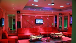 A red upholstered sofa, a coffee table, a flat-screen TV, and a patterned rug in a modern lounge area. - Fushun Tiantian Hotel (Mudanjiang High-speed Railway Wanda Branch) (Mudanjiang)