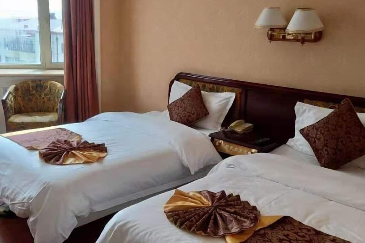 Une chambre d’hôtel avec deux lits, une chaise et une table de chevet avec une lampe.