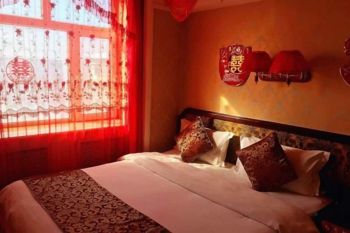 Une chambre d’hôtel avec un lit, des rideaux rouges et des éléments décoratifs sur les murs.