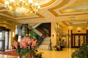 Un amplio vestíbulo con candelabro, escalera y un gran arreglo floral.