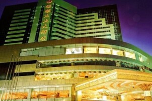 Un hotel de varios pisos con fachada curva, ventanas iluminadas y una entrada destacada con un arco decorativo.