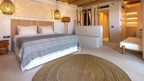 A modern bedroom with a large bed, a bedside table, a woven rug, and a ceiling with wooden beams. - Bohemian Kea Beach Club Resort (Kea)