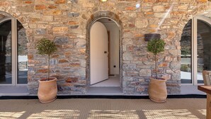 A stone building with a wooden ceiling and two large potted trees. - Bohemian Kea Beach Club Resort (Kea)