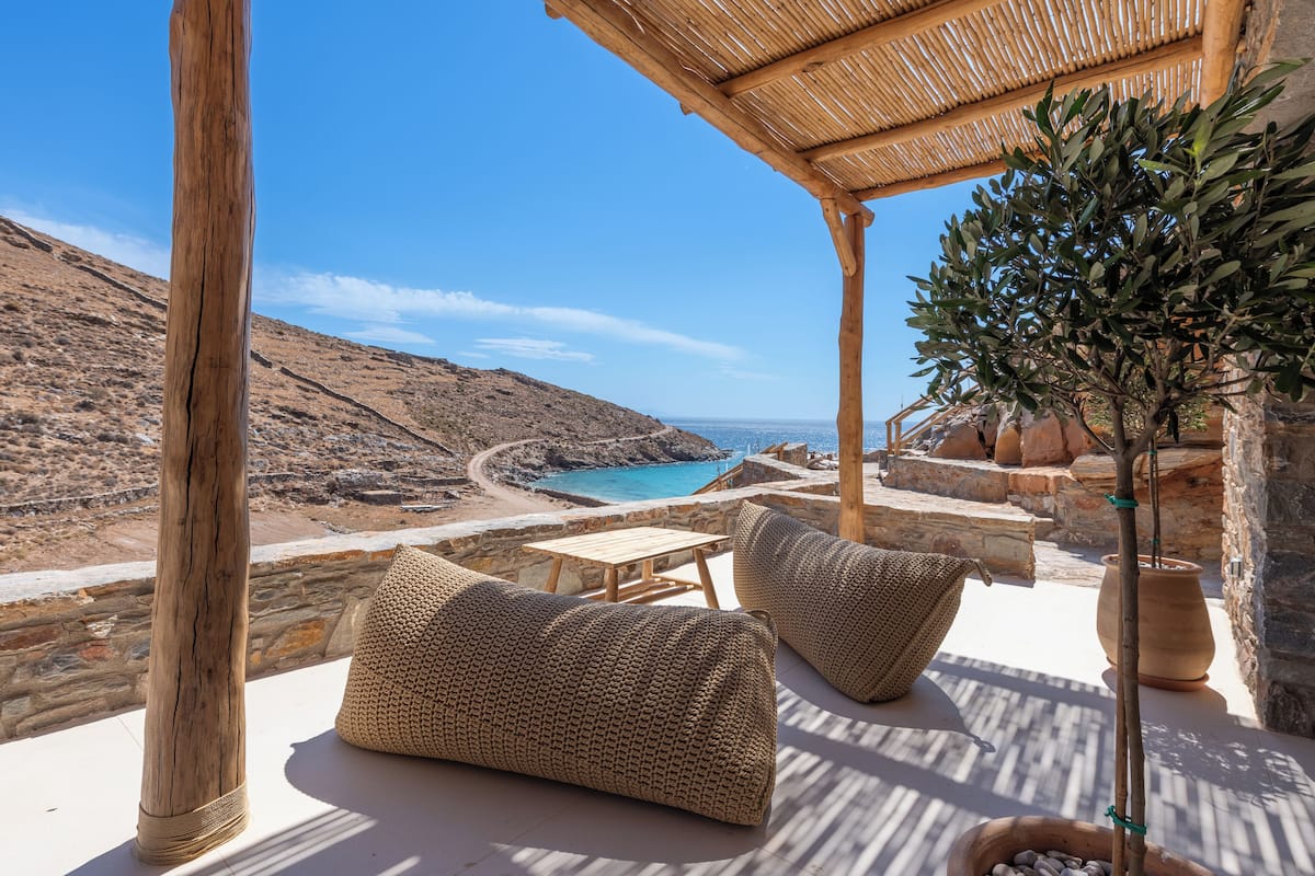 A terrace with a view of the sea, stone walls, and a wooden pergola.
