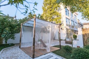 Een houten pergola met een transparant dak in een aangelegde tuin.
