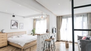 Ein modernes Schlafzimmer mit einem Bett, einer kleinen Bar, einer Couch und einem großen Fenster.