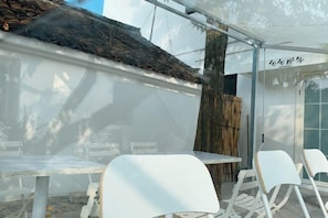 A patio area with tables and chairs, a bamboo fence, and a building with a sign. - Those Years · Joyful Lan · Qijing Garden Homestay (West Gate Scenic Spot) (Tongxiang)