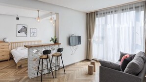 Ein modernes Wohnzimmer mit einer Wand aus Stein, einer Bar mit Hockern, einer Couch und einem Fernseher.