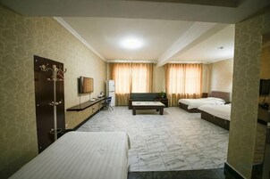 Habitación de hotel con dos camas, un sofá, un televisor y un escritorio.