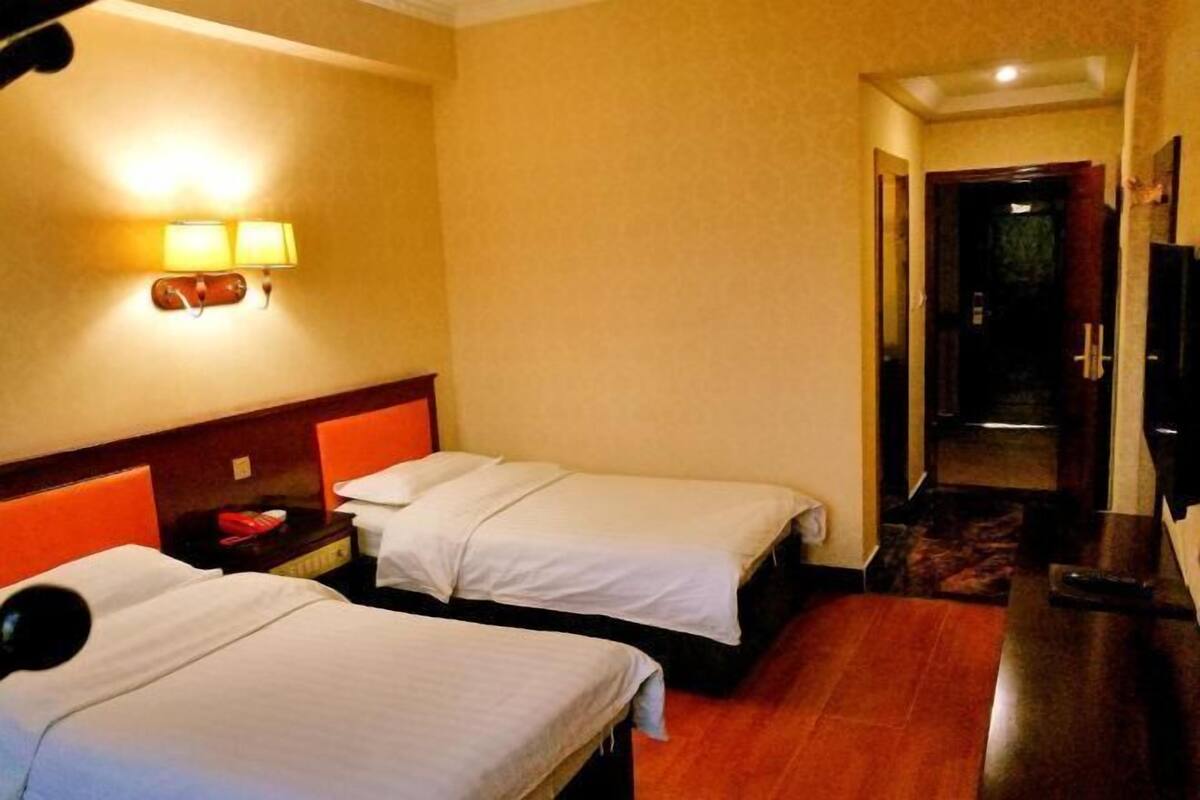 Ein Hotelzimmer mit zwei Betten, einem Nachttisch, einer Lampe und einem Fernseher.
