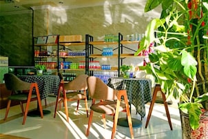 Un restaurante con mesas, sillas, estantes llenos de bebidas y una planta en maceta.