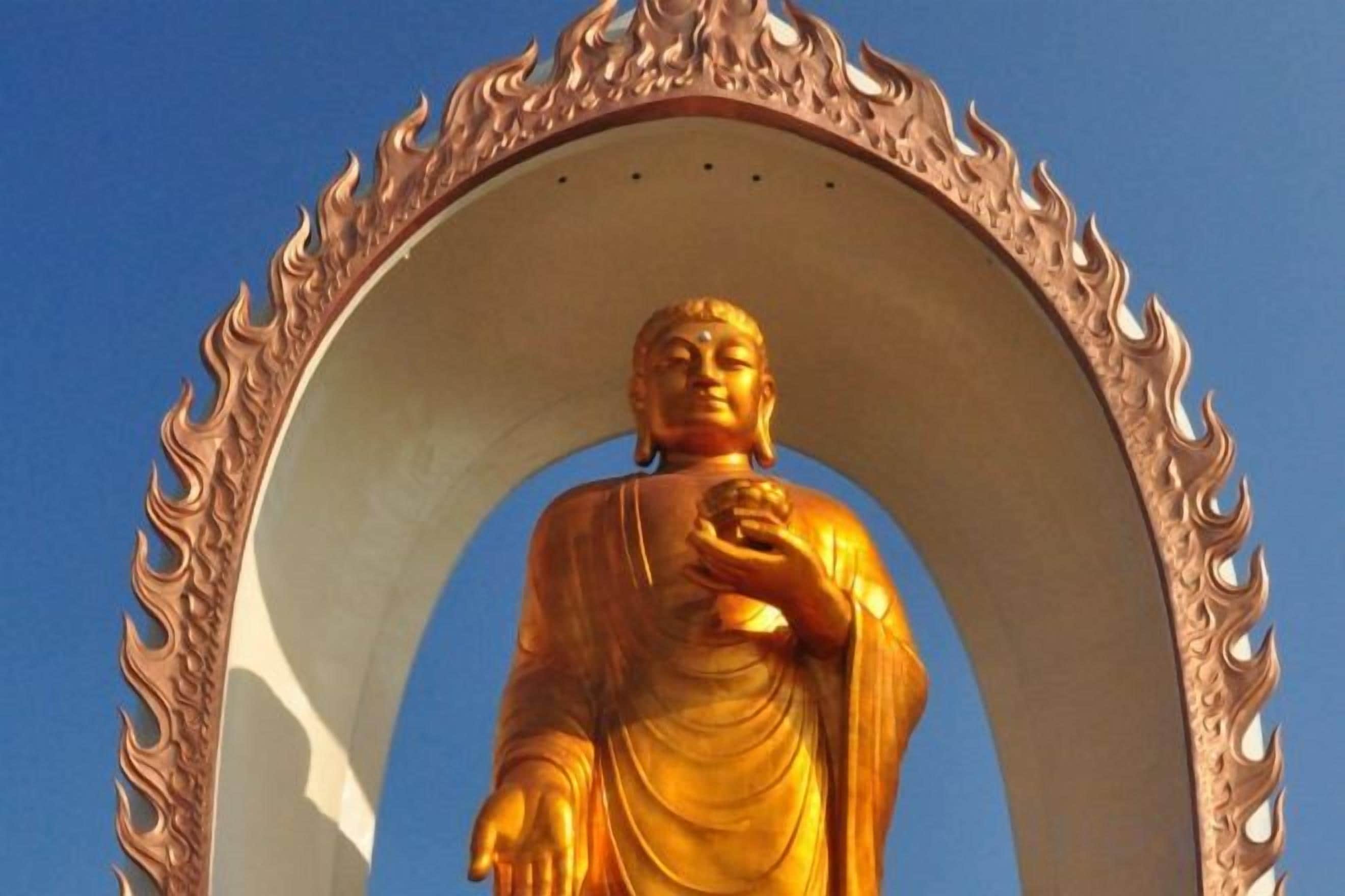 A golden statue of a seated figure within an ornate, flame-like arch.