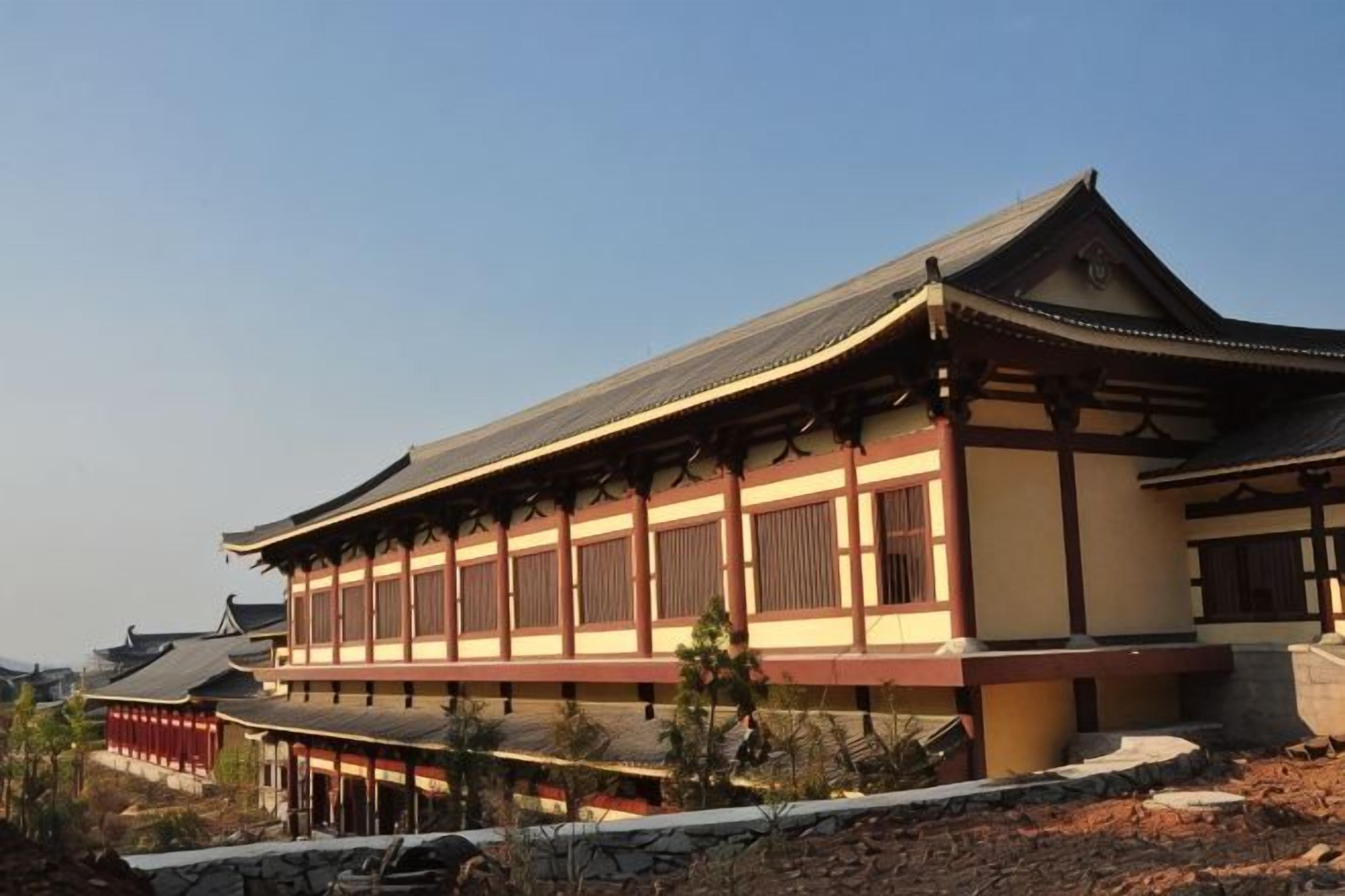 A traditional building with a curved roof, multiple windows, and a stone pathway leading to it.