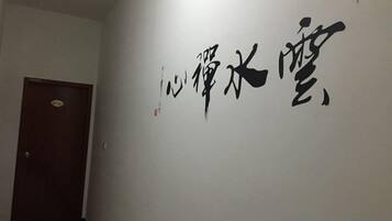 A hallway with a door and a wall with large black calligraphy.