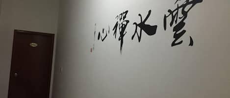 Un pasillo con una puerta y una pared con caligrafía negra de gran tamaño.