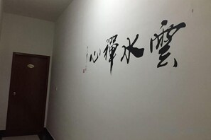 A hallway with a door and a wall with large black calligraphy. - Lushan Hanshe Homestay (Donglin Buddha) (Lushan City)
