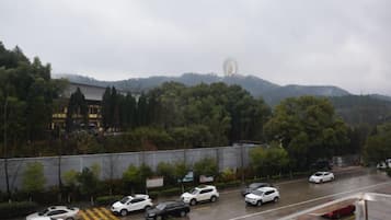 Un estacionamiento con coches y una vista de una colina con árboles y un edificio al fondo.