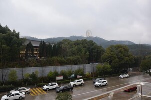 Un estacionamiento con coches y una vista de una colina con árboles y un edificio al fondo.