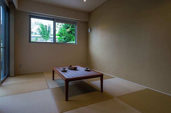 A room with tatami flooring, a wooden table with a basket and cups, and a window with a view of greenery. - Pool Villa Yagaji Island by Coldio Premium (Nago)