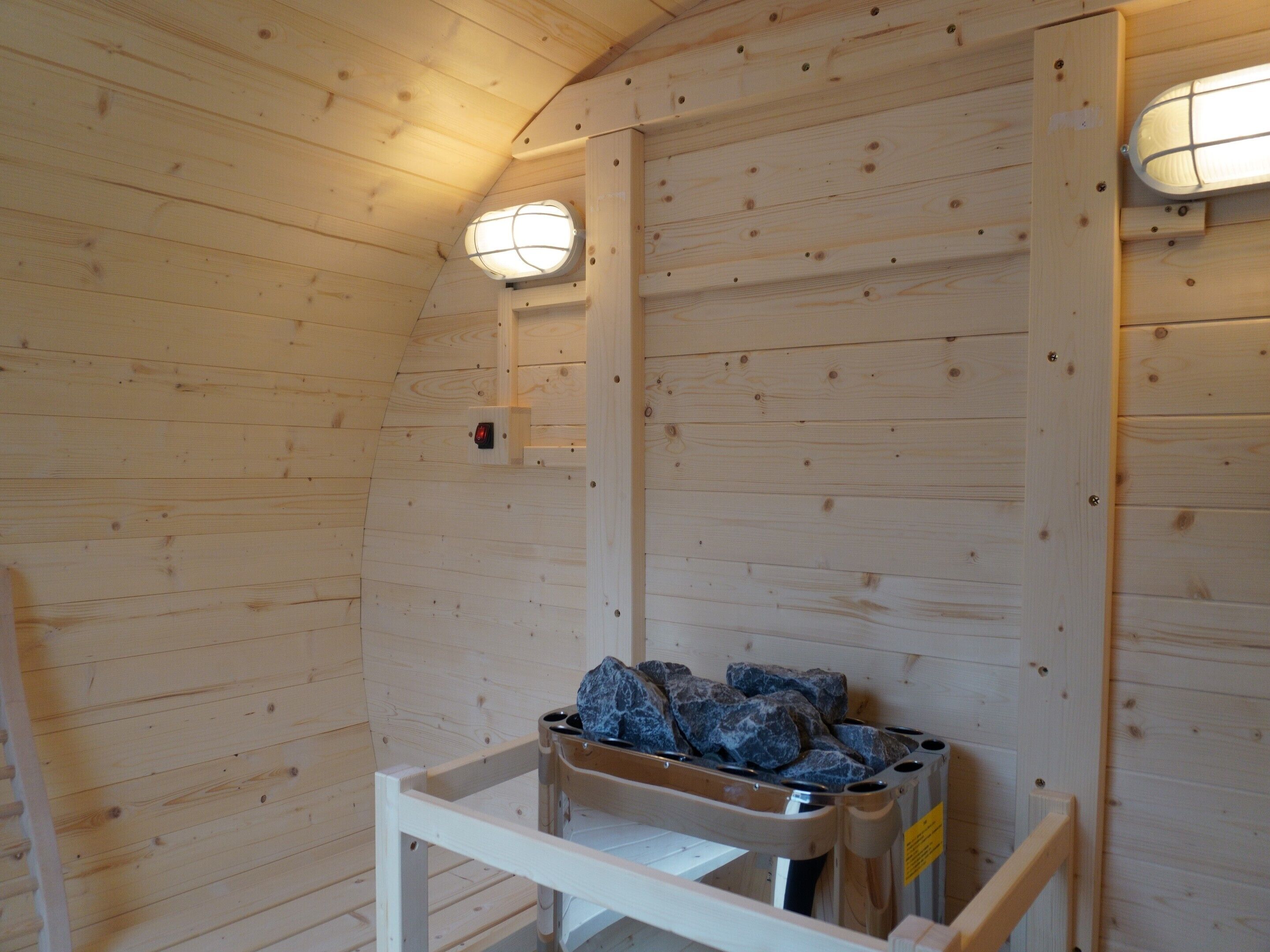 Ein Holzblockhaus-Innenraum mit einer Bank, einem Wandheizgerät und einem Fenster.