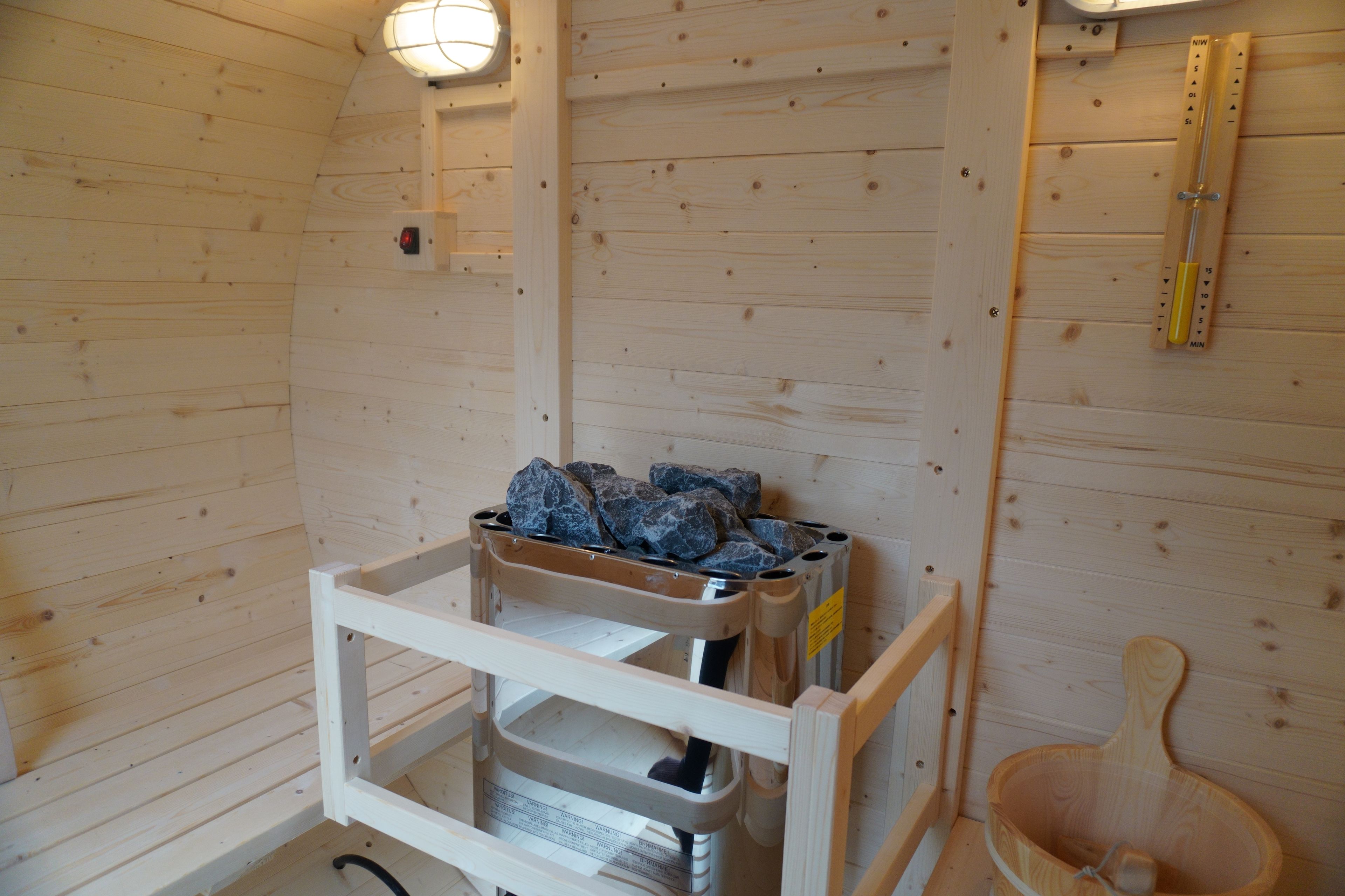 Interior de una cabaña de madera con sauna, un banco de madera y un calentador de sauna.