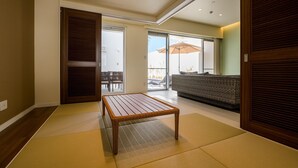 A room with tatami flooring, a wooden table, a sofa, and a sliding door.
