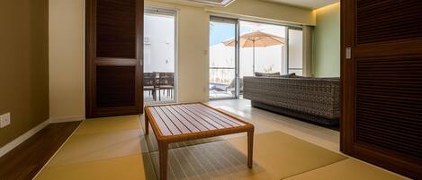 A room with tatami flooring, a wooden table, a sofa, and a sliding door.