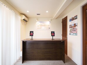 A reception desk with two digital kiosks, a map on the wall, and a wooden door. - Pool Villa Yagaji Island by Coldio Premium (Nago)