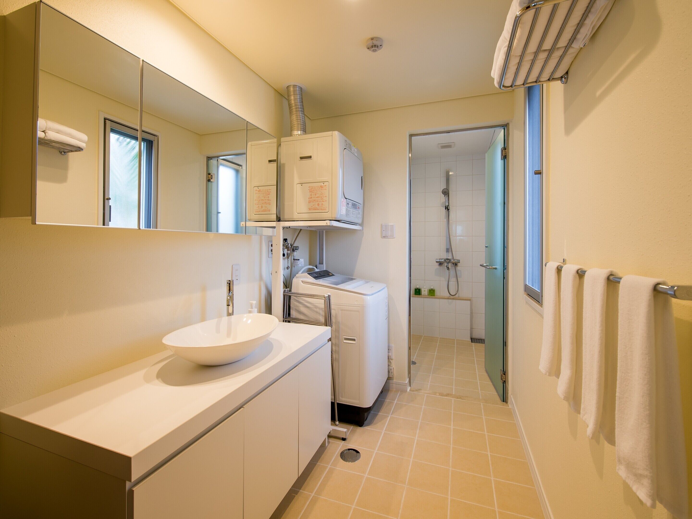 A modern bathroom with a large mirror, a sink, a shower, and a towel rack.