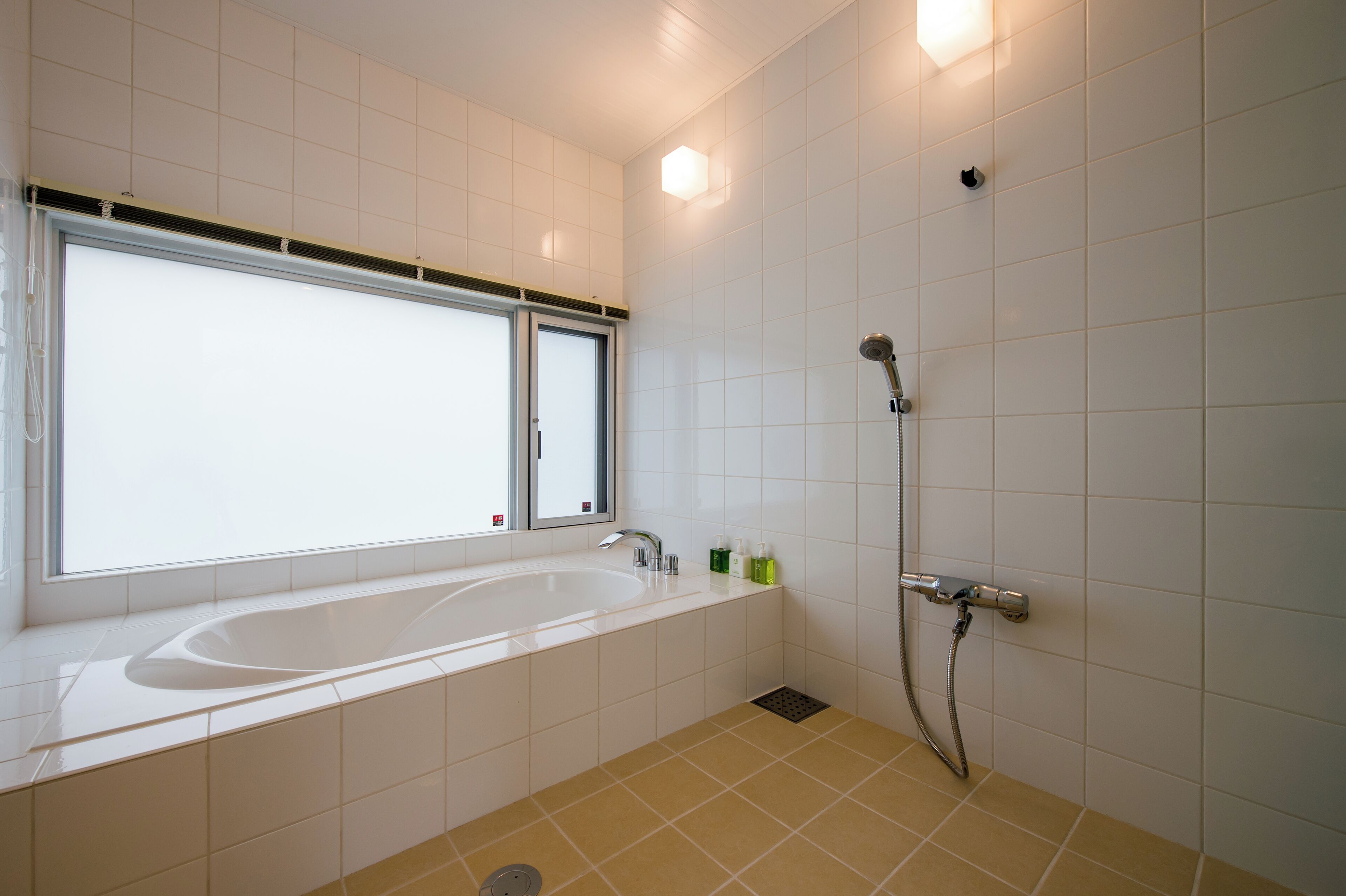 A modern bathroom with a large bathtub, a shower, and a window.