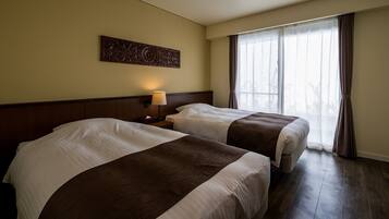 A hotel room with two beds, a nightstand with a lamp, a decorative wall piece, and a large window with curtains.