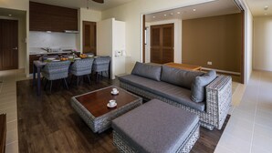 A modern living room with a sofa, ottoman, and dining area with chairs and a table.