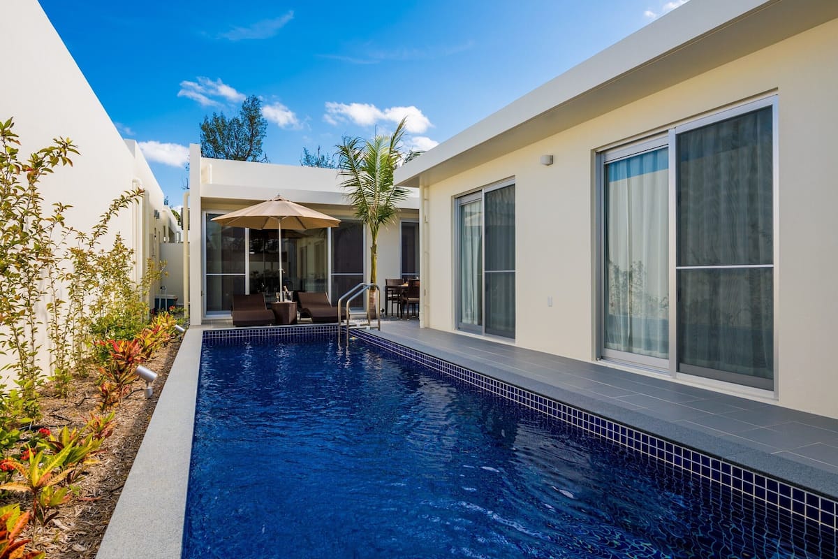 A modern pool area with a clear blue pool, lounge chairs, and a covered seating area.