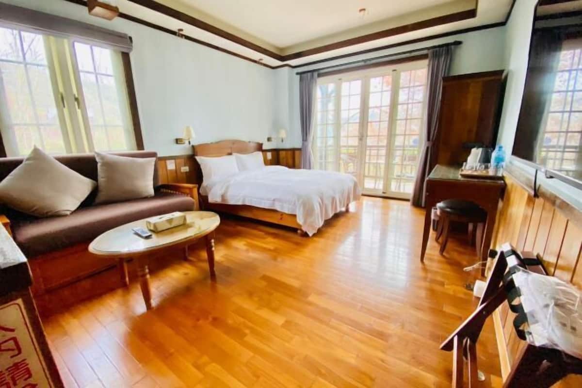 A hotel room with a bed, sofa, coffee table, and a desk with a chair.
