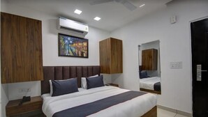 Ein modernes Hotelzimmer mit einem großen Bett, einem Holzkopfende, einem Gemälde an der Wand und einem Spiegel über dem Bett.