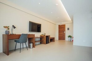 A modern room with a wooden desk, a chair, a television, and a door.