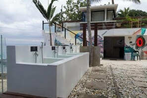 A modern outdoor pool area with a glass-enclosed jacuzzi, a staircase leading to a building, and a palm tree. - Solitude Acacia Resort (Mabini)