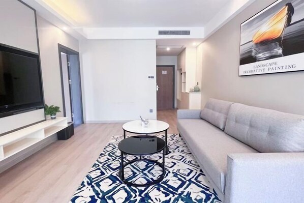 Un salon moderne avec un canapé, une table basse, un téléviseur et un tapis à motifs.