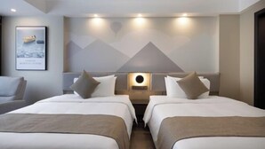 Ein Hotelzimmer mit zwei Betten, einer Wandleuchte und einem gerahmten Bild an der Wand.