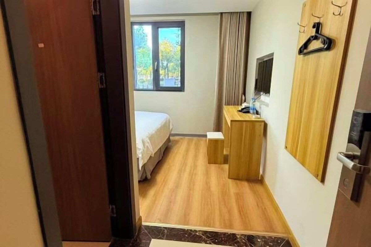 Een hotelkamer met een bed, een bureau, een spiegel en een raam.
